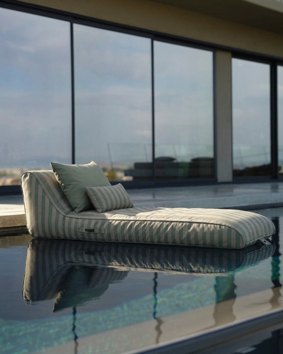 Modern sun lounge  in a pool with large glass windows in the background