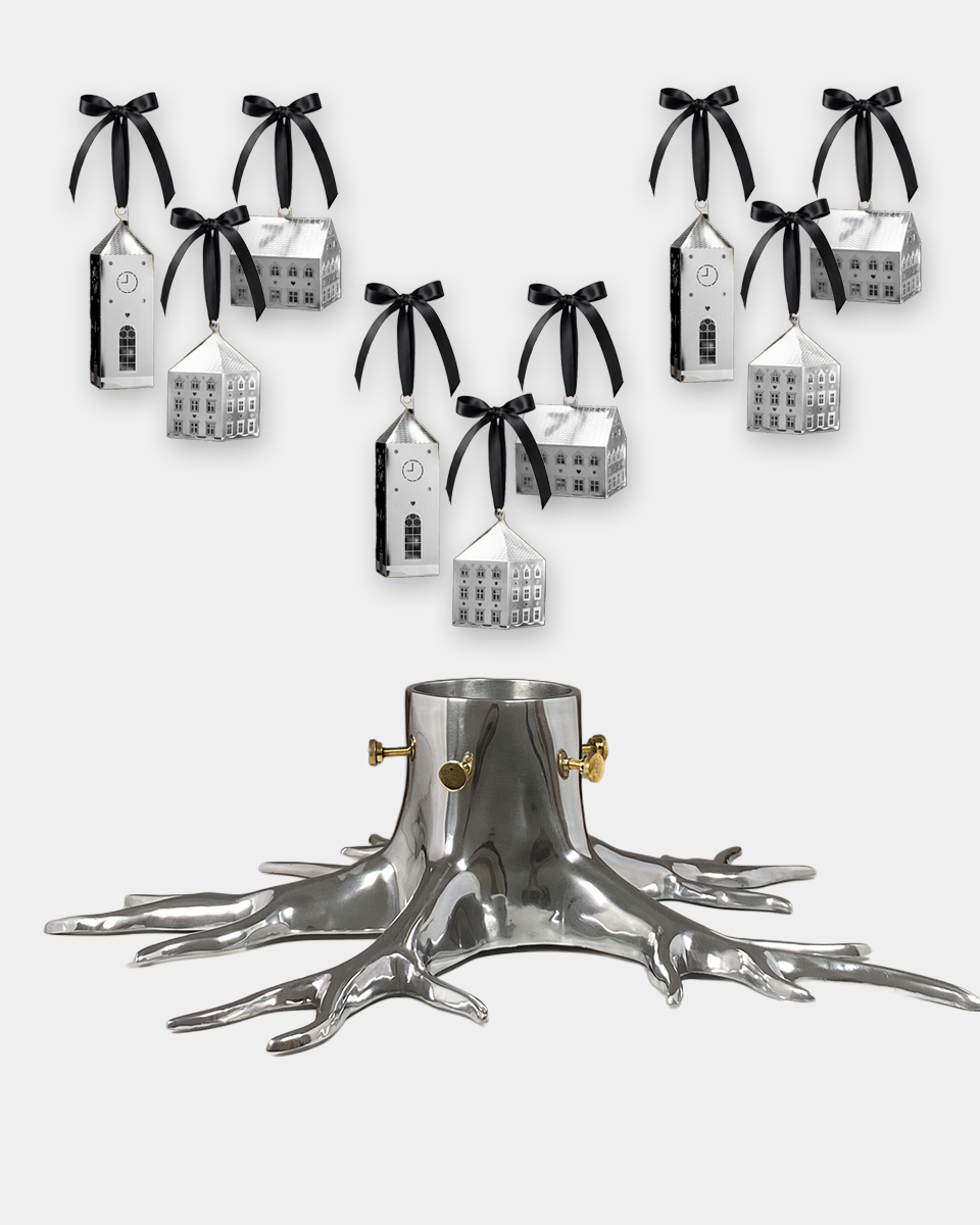 A silver tree stump Christmas tree holder with ornate branch-like feet, shown with multiple small silver house ornaments hanging from black ribbons above it on a light gray background.