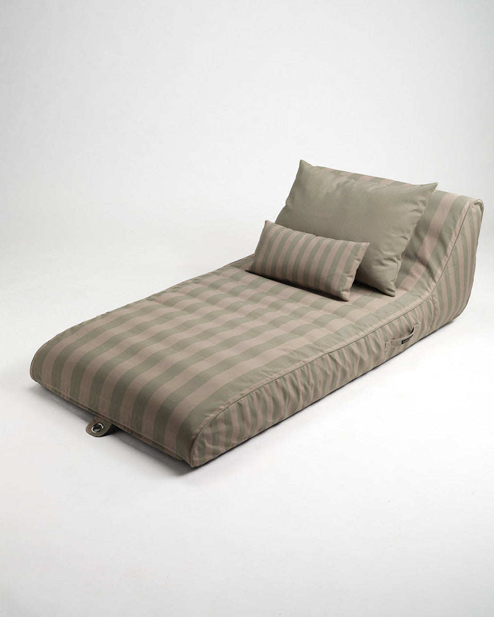 Green and beige striped sun lounger with pillows on a white background