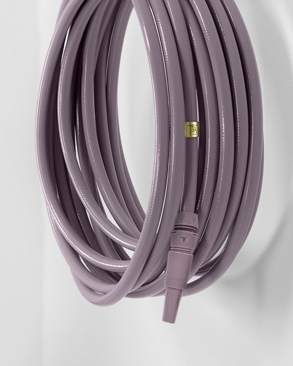 purple garden hose with a gold valve on a light gray background