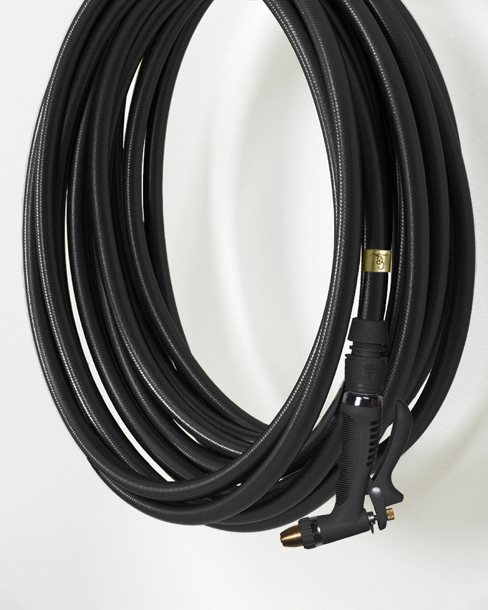 black garden hose with brass connectors on a white background