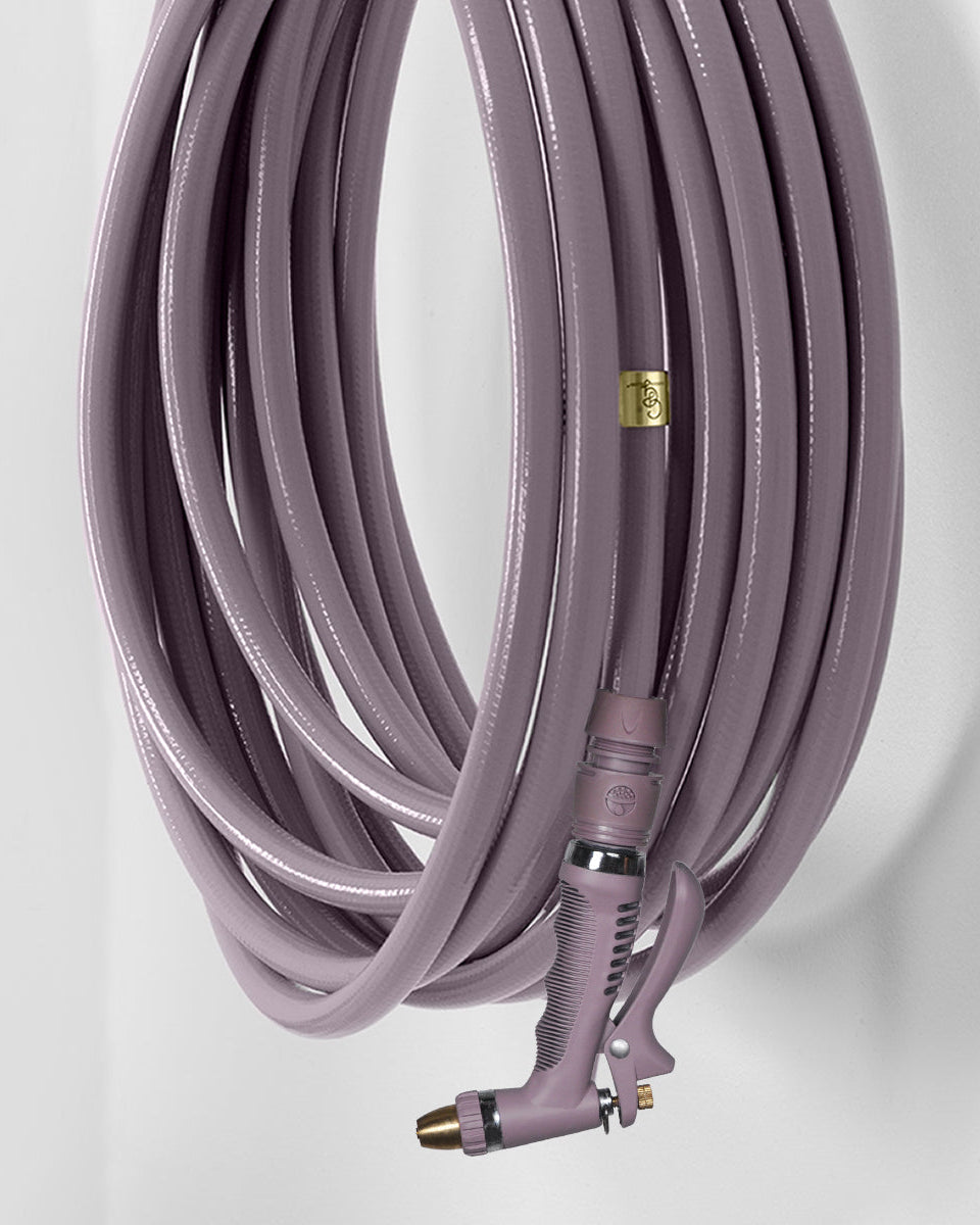 purple garden hose with a nozzle on a light gray background